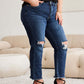 Woman wearing RFM Jeans Crop Dylan Tummy Control Distressed High Waist Raw Hem Jeans and black heels in a stylish living room setting