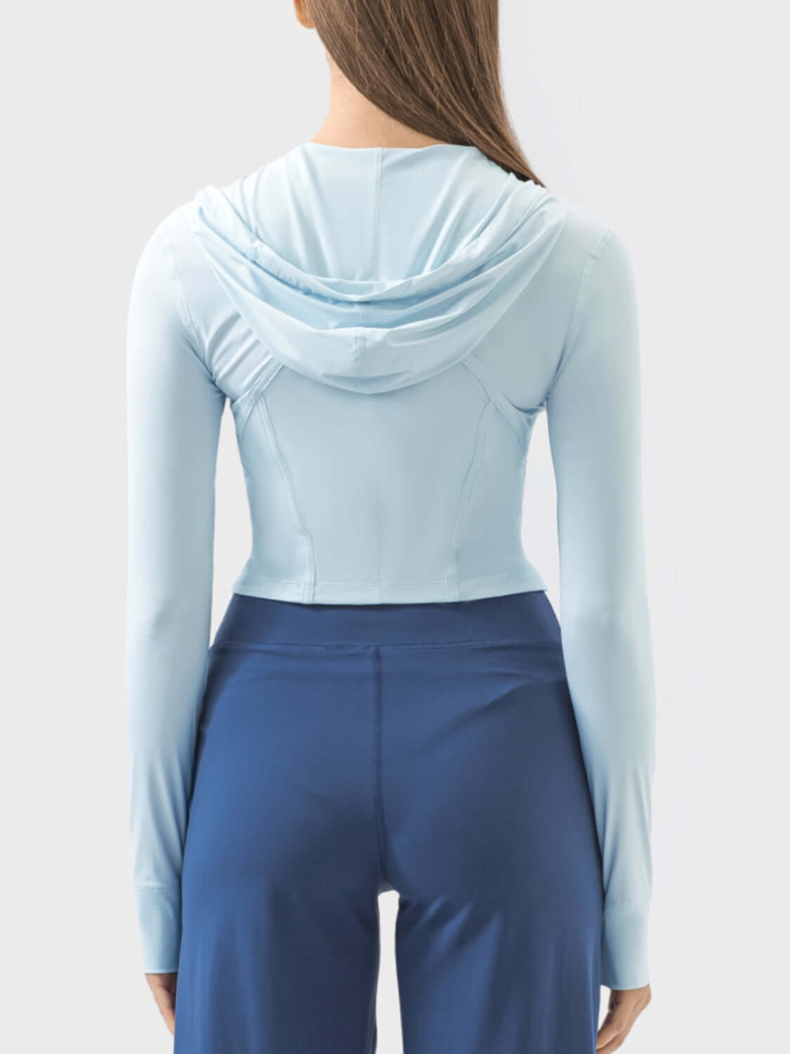 Back view of a woman wearing a light blue zip-up hooded long sleeve active outerwear, showcasing a sleek design and comfortable fit.