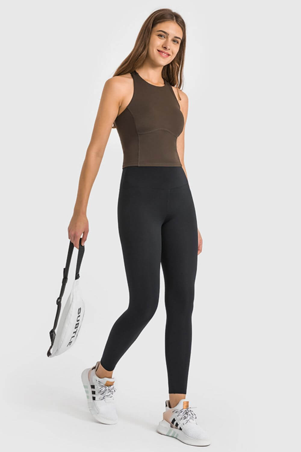 Stylish model in high waist ankle-length black yoga leggings and a brown top, ready for a workout.