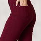 Woman wearing Hyperstretch Mid-Rise Skinny Jeans by YMI Jeans in deep burgundy, showing back pocket detail for a stylish and comfortable fit.