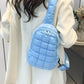 Woman in white coat wearing blue quilted nylon crossbody bag with a stylish puffy design.