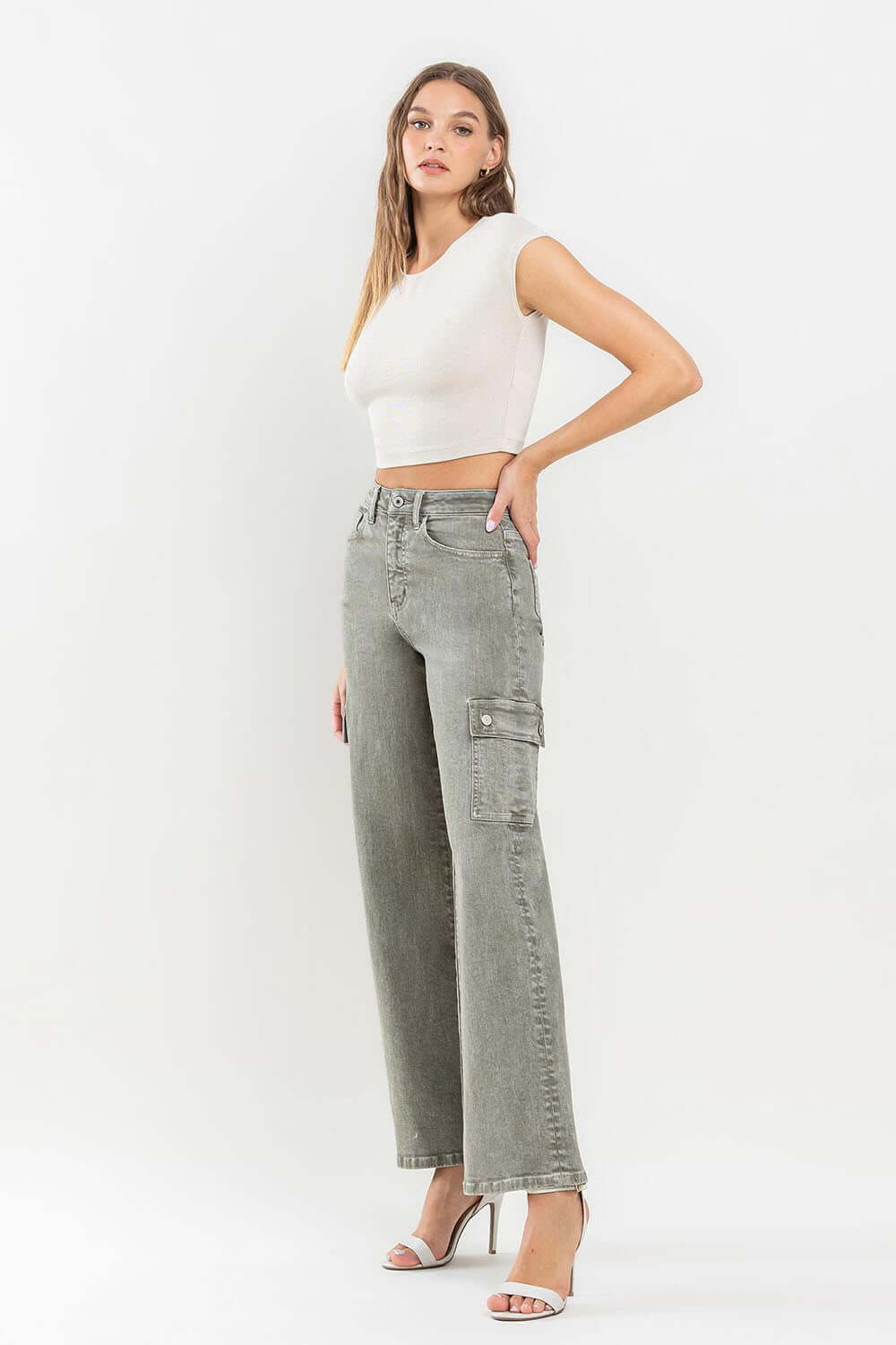 Woman wearing 90's super high rise loose cargo jeans with ultra-high waist and cargo pockets, paired with a white crop top and heels.