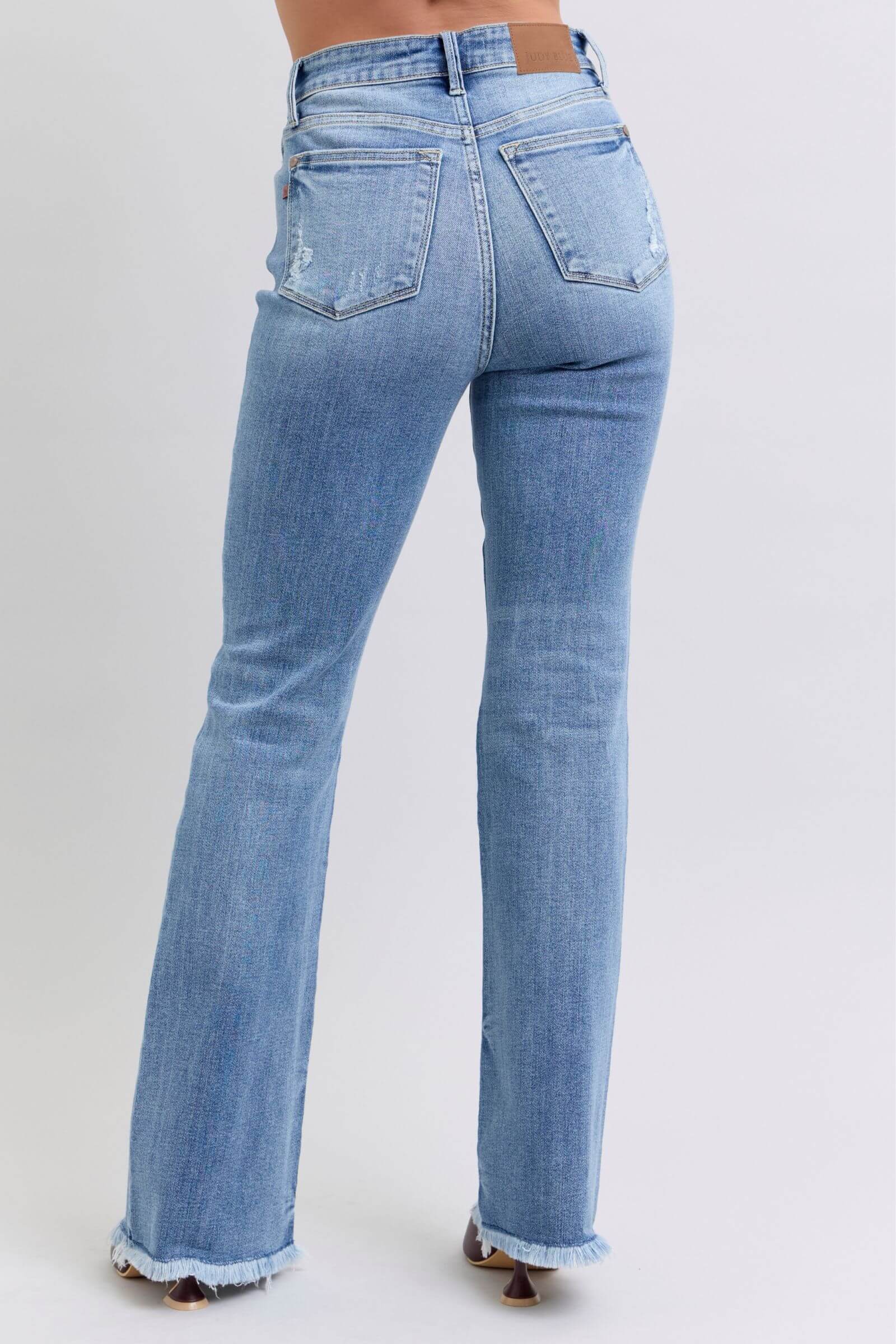 Judy Blue high rise bootcut jeans with raw hem, featuring a flattering fit and stylish vintage-inspired look.