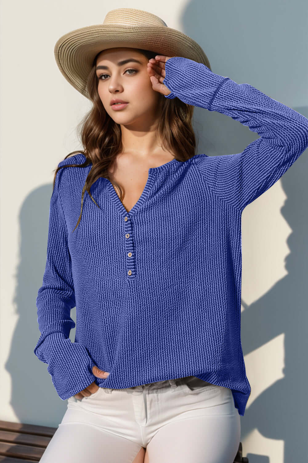 Woman wearing blue full size notched thumbhole long sleeve t-shirt with hat and white pants