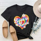 Black graphic round neck short sleeve T-shirt with "Love is Love" rainbow heart design, paired with tan shoes and a hat.