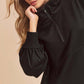 Stylish woman modeling a black exposed seam half zip drop shoulder sweatshirt with relaxed fit and casual elegance.