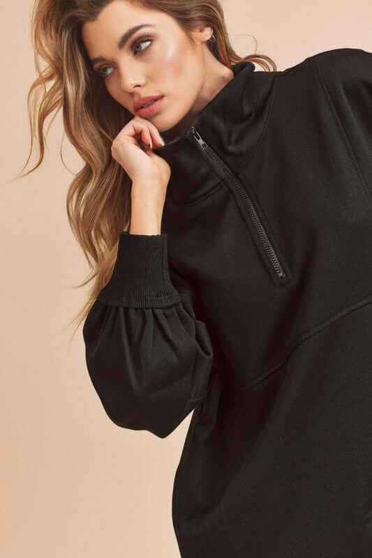 Stylish woman modeling a black exposed seam half zip drop shoulder sweatshirt with relaxed fit and casual elegance.