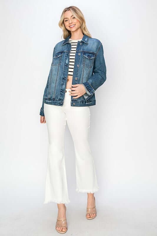 Stylish woman in a distressed denim button-up jacket paired with white flared pants and a striped top, exuding casual chic vibes.