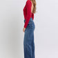 Model showcasing Judy Blue full-size raw hem mid-rise jeans in a stylish, relaxed fit with a red top.