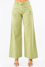 High waist distressed wide leg jeans in soft green, stylishly worn with a chic pair of sandals.