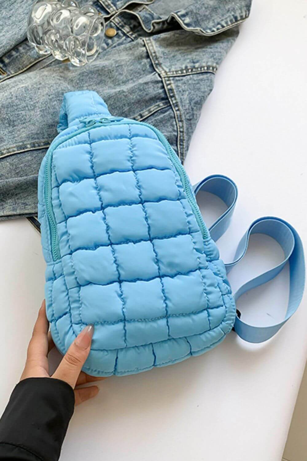 Trendy blue quilted nylon crossbody bag on a casual outfit background, perfect for stylish adventures.