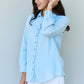 Woman wearing Blue Jean Baby Denim Button Down Shirt Top in Light Blue with long sleeves and white shorts.