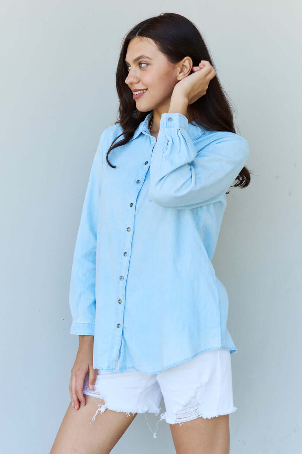 Woman wearing Blue Jean Baby Denim Button Down Shirt Top in Light Blue with long sleeves and white shorts.