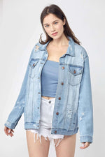 Woman wearing Risen Jeans distressed long sleeve denim jacket with vintage detailing over a blue top and white shorts