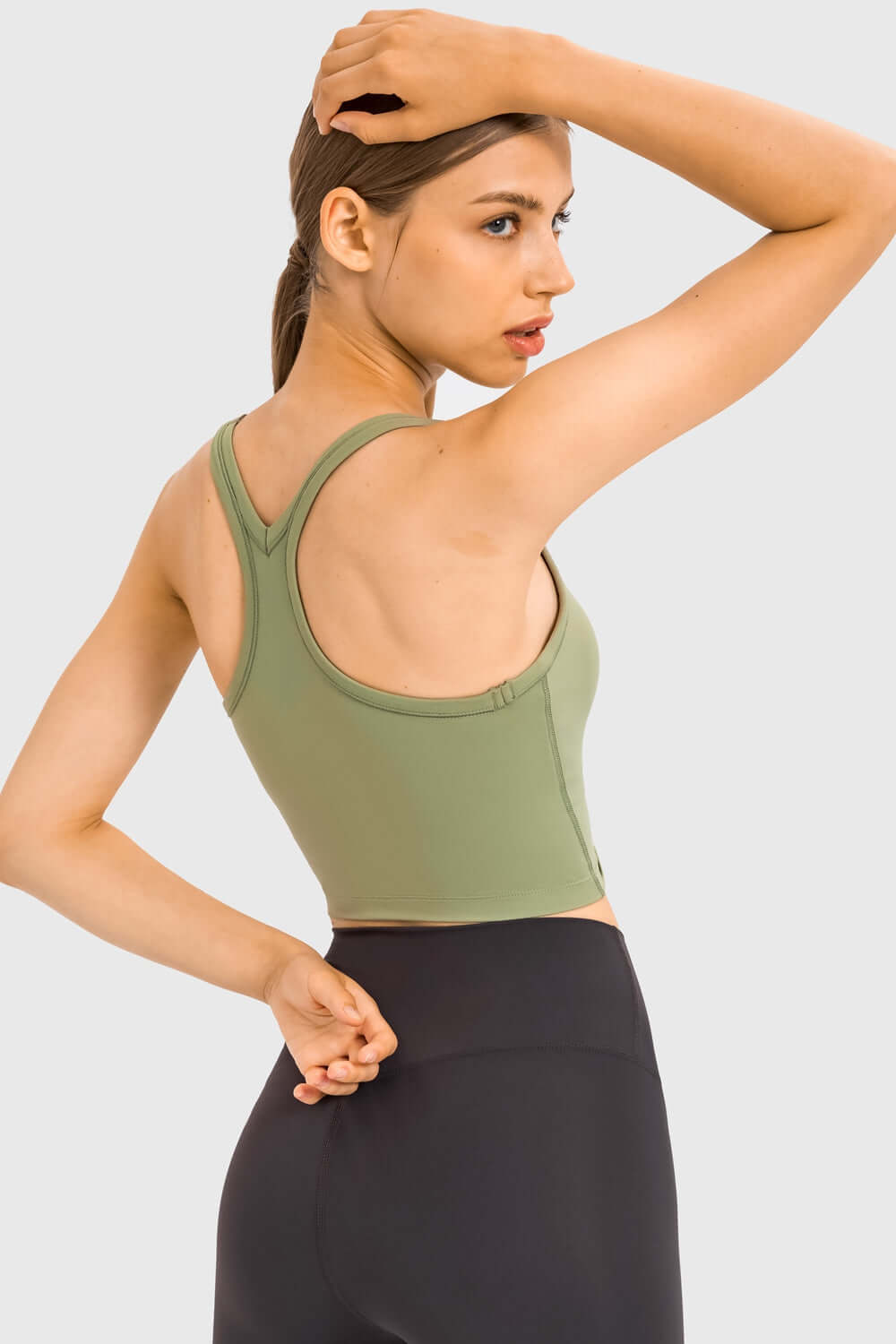 Stylish model showcasing the Millennia Racerback Sports Bra in olive green, perfect for yoga and active workouts.