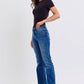 Model showcasing Judy Blue mid-rise bootcut jeans with thermal lining, styled in a chic black top and ankle boots.