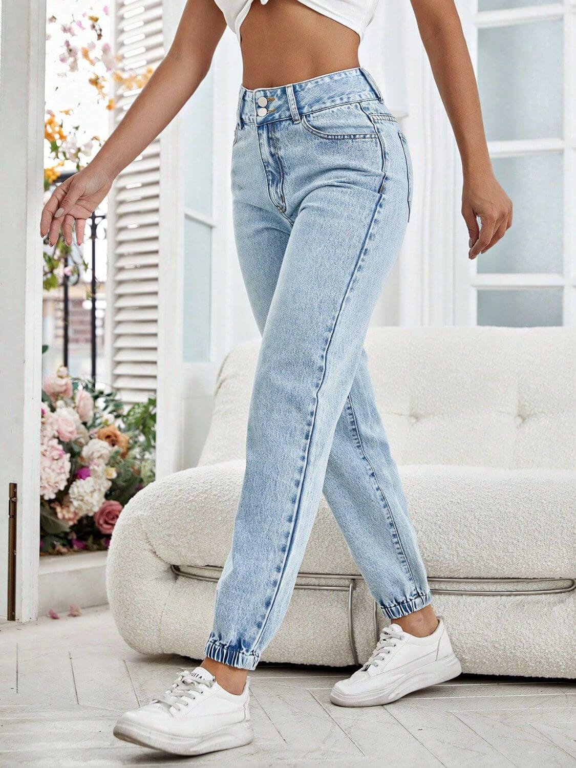 Woman wearing Bella Road High Waist Jeans with pockets and white sneakers in a stylish living room setting