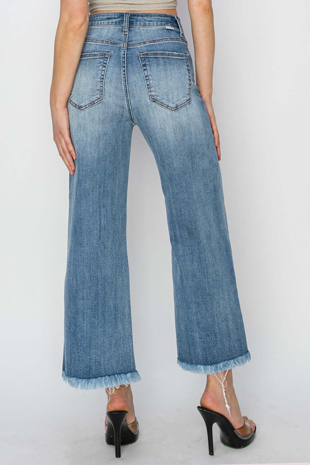 High-rise, raw hem, cropped wide leg jeans from Risen Jeans, back view showing trendy stylish design and frayed hem detail.