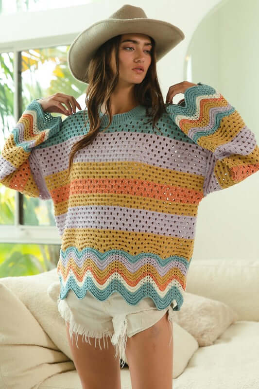 Wavy hem openwork sweater in colorful stripes, worn with shorts and a hat, perfect for a trendy casual look.