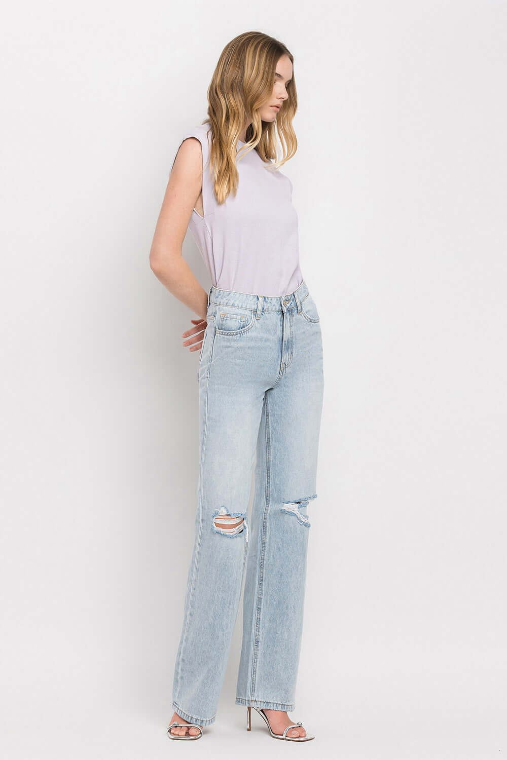 Woman wearing 90's Vintage Super High Rise Flare Jeans with a white top, featuring super high-rise waist and wide flare legs.