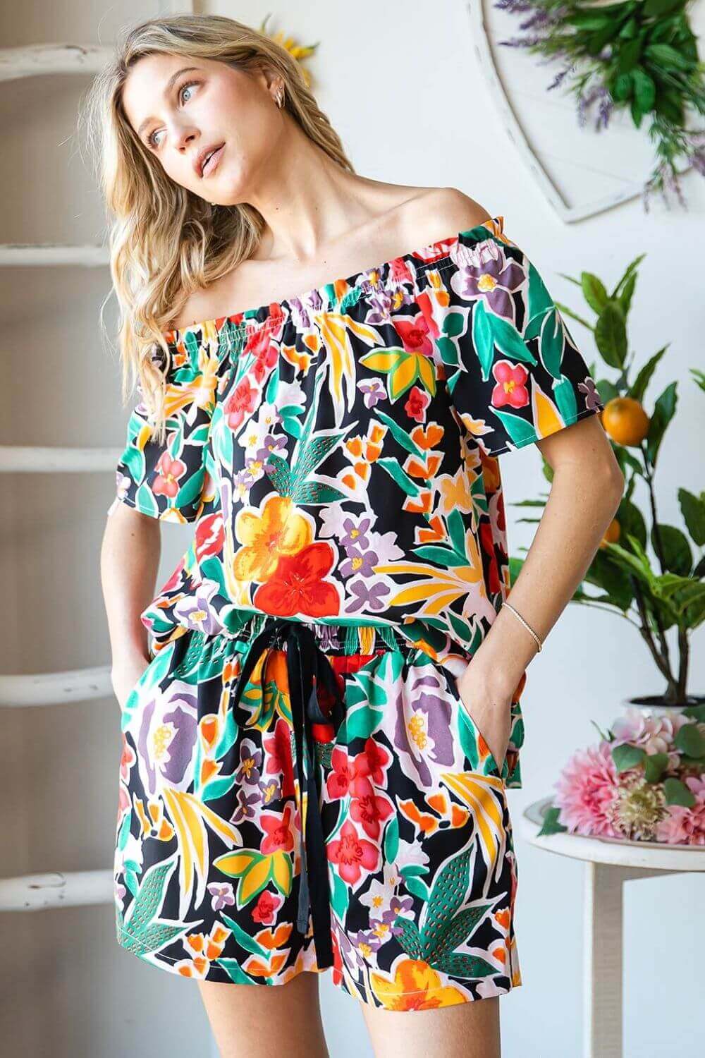 Woman wearing a floral off-shoulder top with a colorful print, perfect for a summery and casual look.