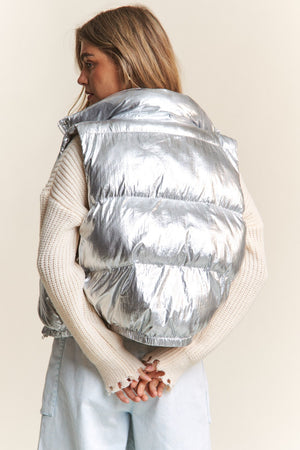 Trendy metallic puffer vest with snap and zipper closures for stylish warmth and easy layering.