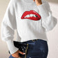 Woman wearing Bella Road Lip Turtleneck Long Sleeve Sweater, featuring red lip design, paired with dark jeans and a black clutch.