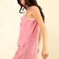 Woman wearing chic pink half button drawstring sleeveless romper perfect for casual day out or fun night with friends