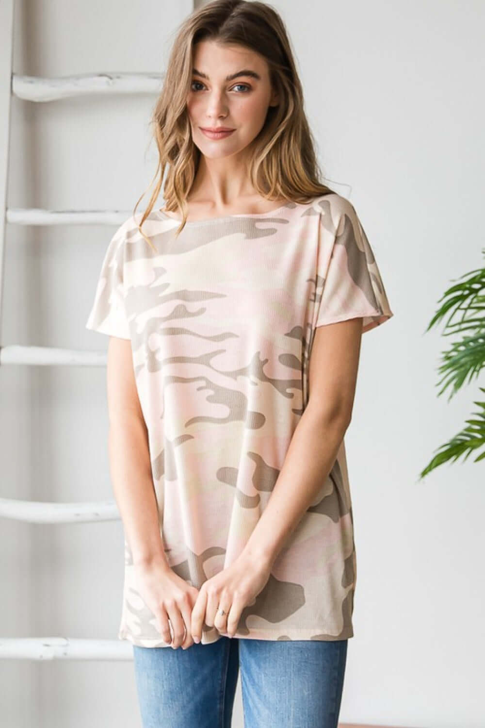 Woman wearing short sleeve round neck camouflage tunic T-shirt in studio setting, casual and lightweight fabric.