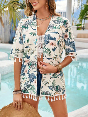 Model in Bella Road Swim Tassel Cover-Up with floral print by the pool, showcasing half sleeves and playful tassel details.