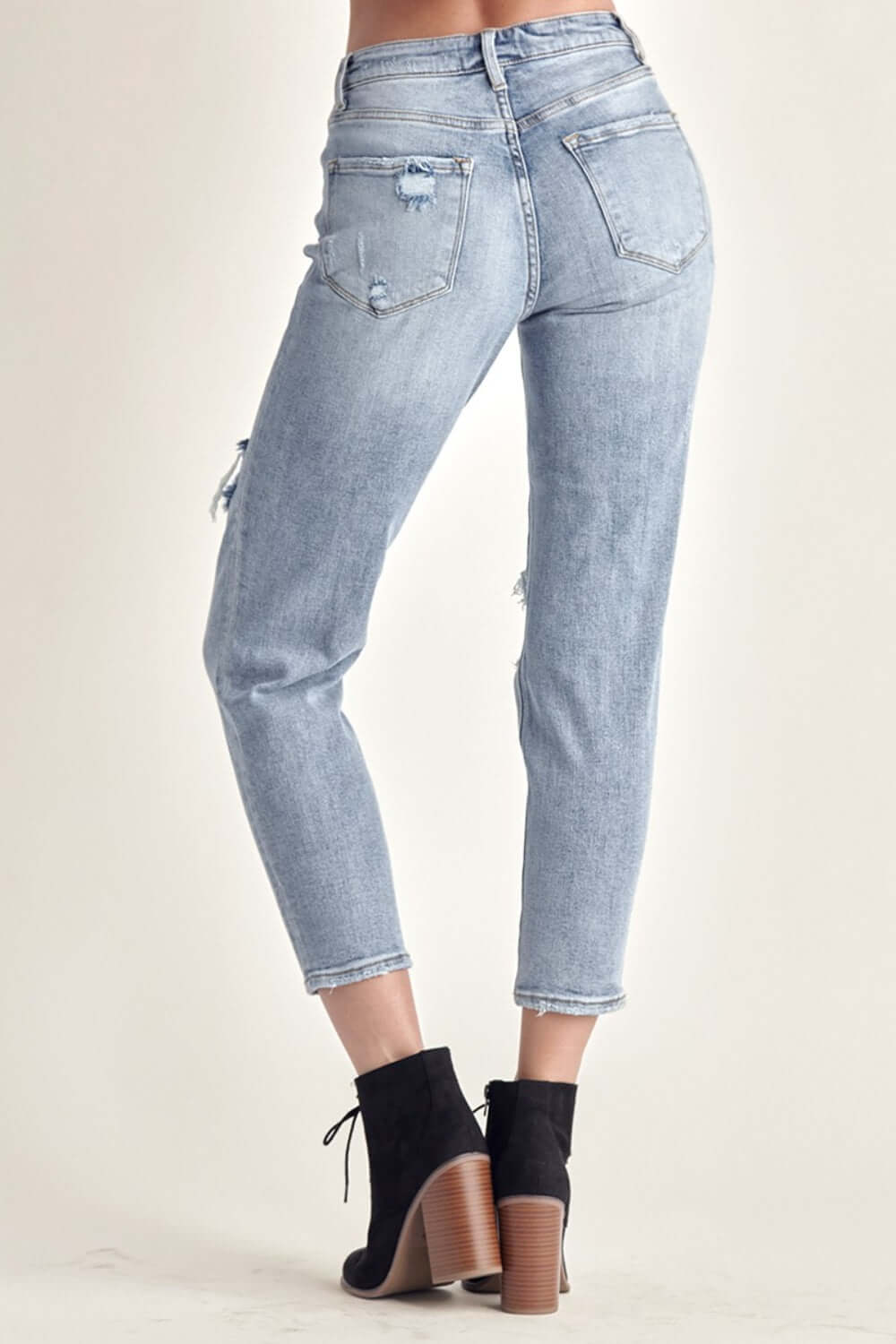 Woman modeling Risen distressed slim cropped jeans, showcasing the flattering fit and stylish distressed details from the back.