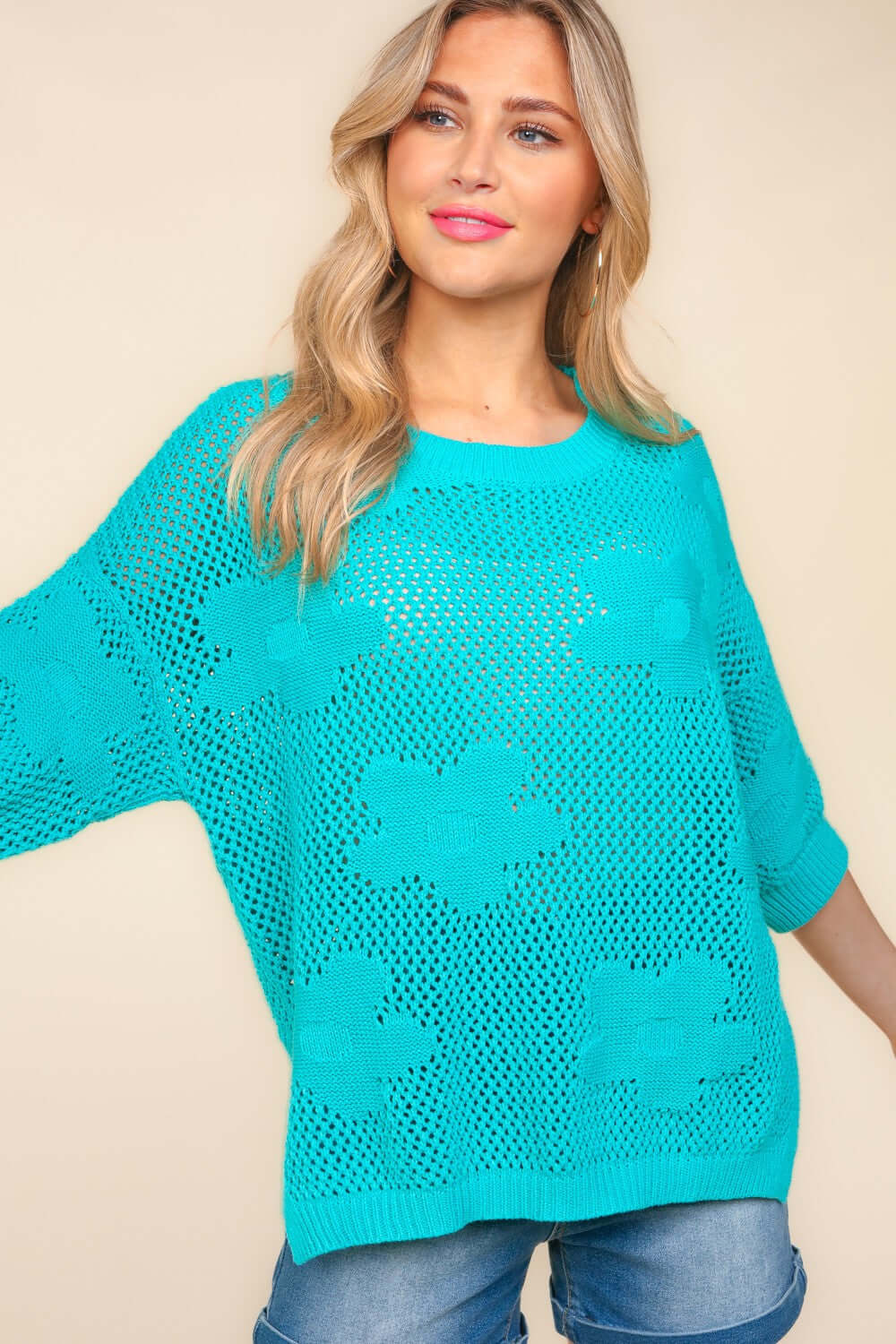 Woman wearing a teal floral crochet side slit knit top with jeans, showcasing the stylish and feminine floral crochet design.