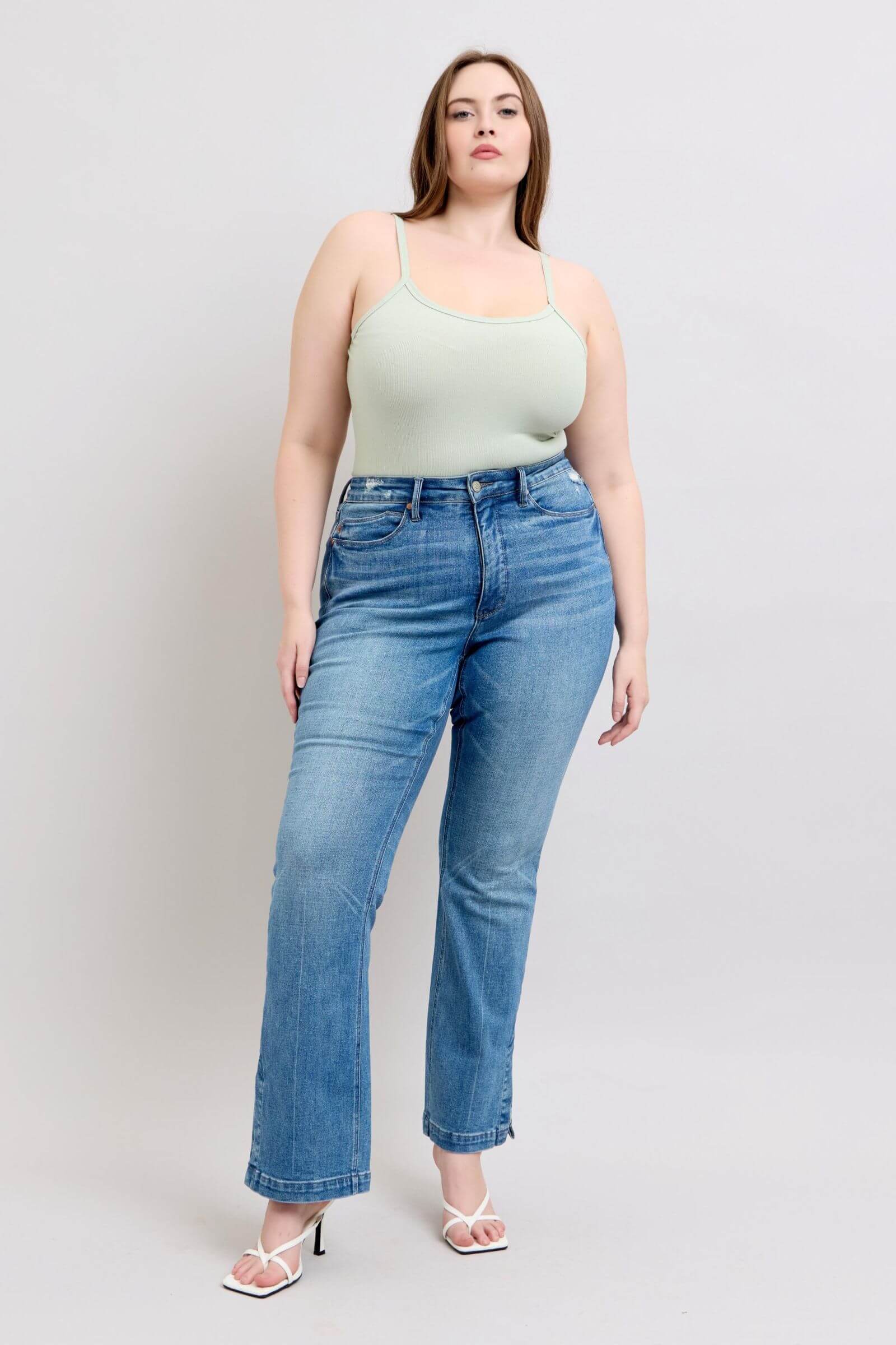 Model showcasing high waist tummy control vintage wash side slit slim bootcut jeans with a light green top.