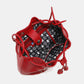 Nicole Lee USA red studded bucket bag with drawstring and snap button closure, showing interior printed polyester lining and zippers.