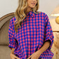 Woman wearing a Plaid Button Up Dolman Sleeve Shirt with a classic plaid pattern in pink and blue, styled with white jeans