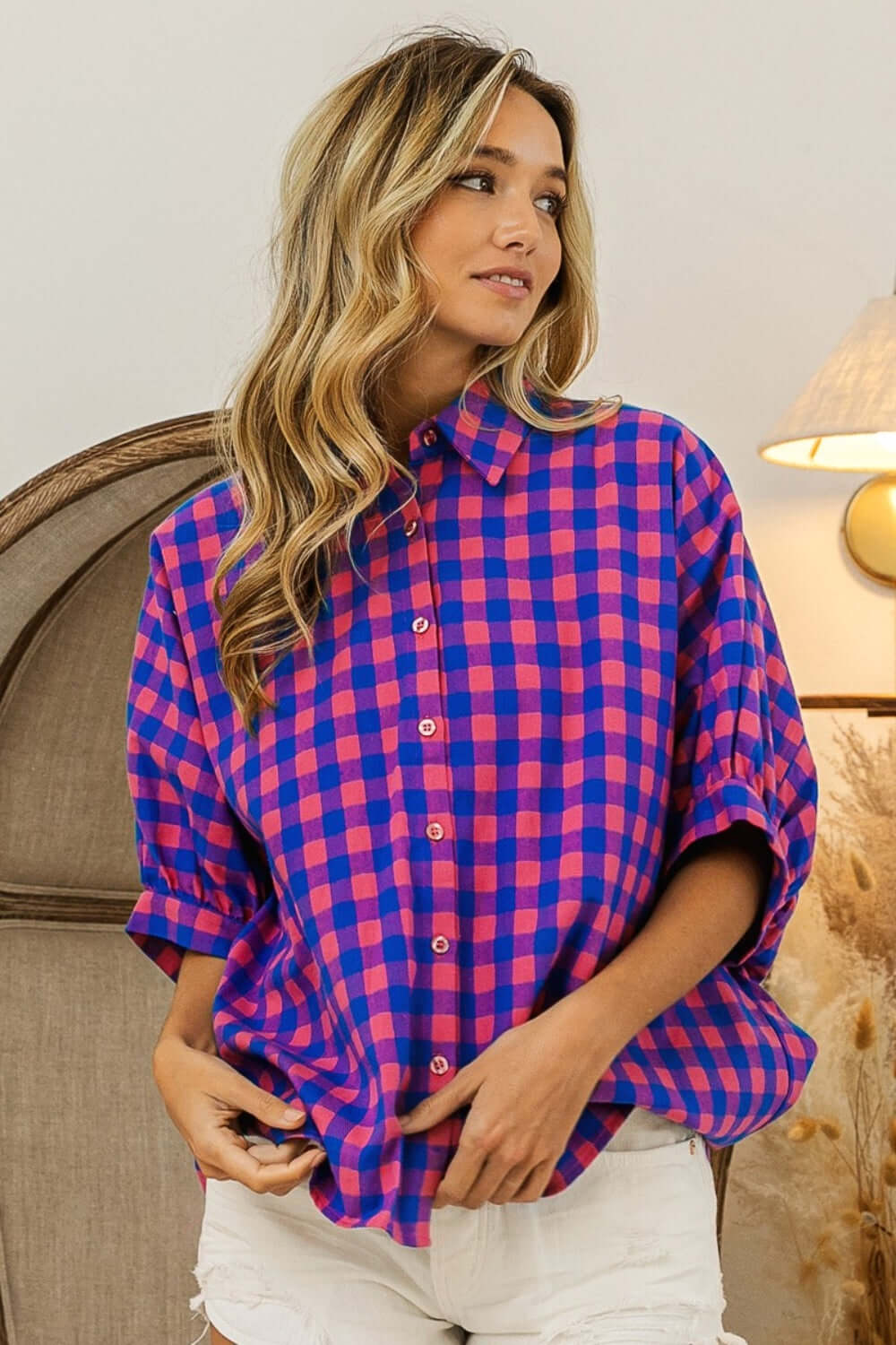 Woman wearing a Plaid Button Up Dolman Sleeve Shirt with a classic plaid pattern in pink and blue, styled with white jeans