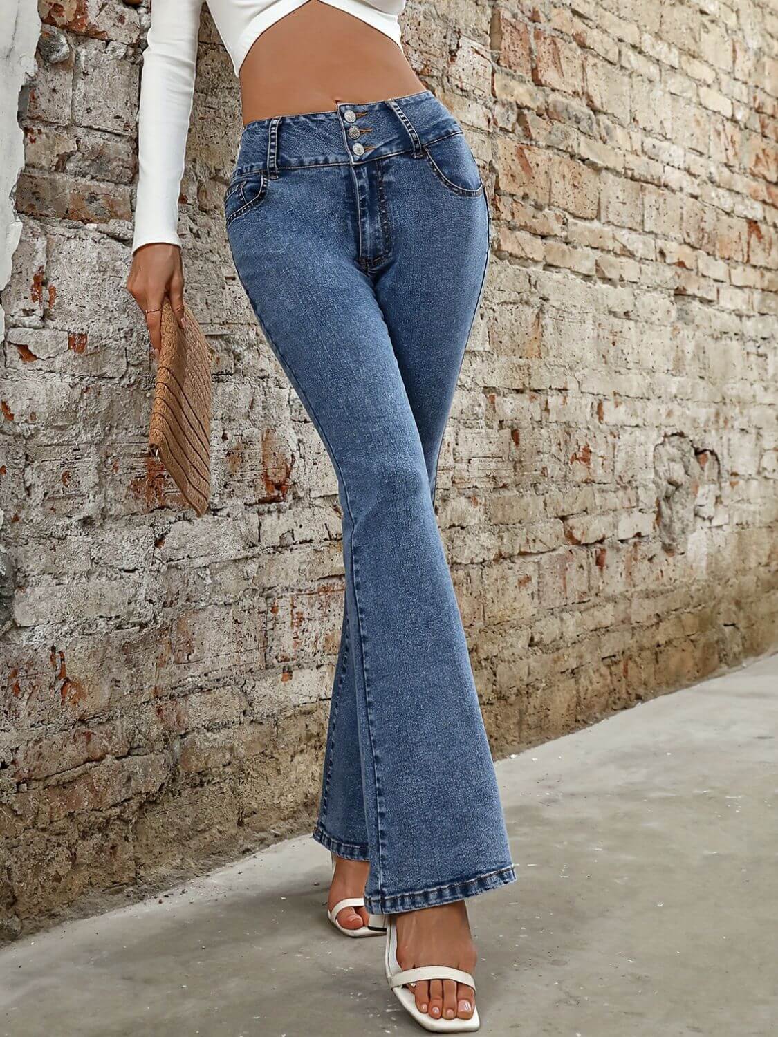 Bella Road bootcut jeans in medium wash, featuring pockets, styled for a chic casual look against a textured wall.