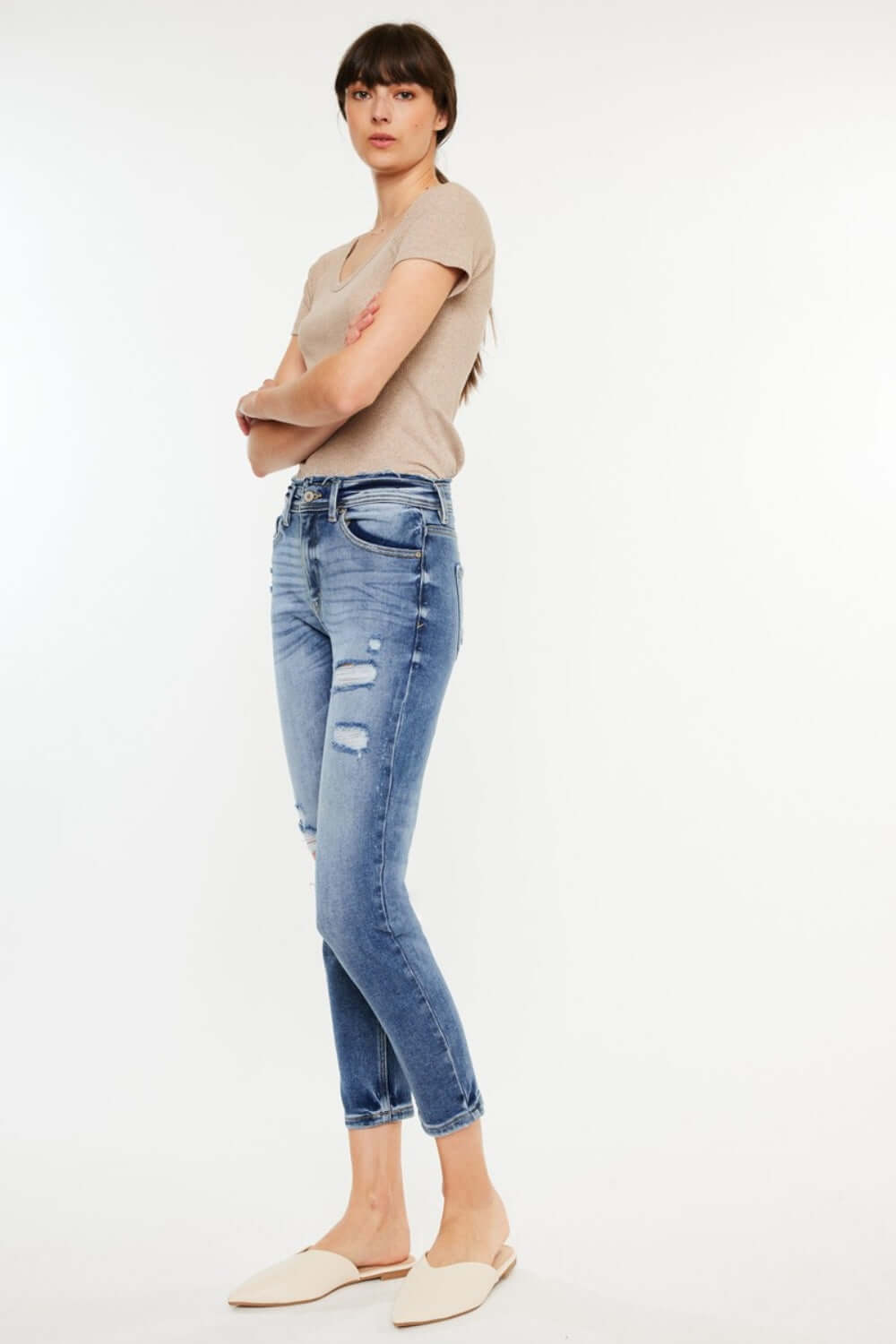 Woman wearing High Rise Distressed Mom Jeans paired with a beige top and white flats, showcasing a chic and comfortable style.