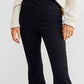 Woman wearing black Asymmetric Waist Flare Jeans with unique waistline design, paired with a cozy white sweater.