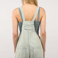 Back view of woman wearing washed frayed hem denim overall romper with side and back pockets, showcasing vintage and eco-friendly casual fashion.