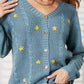 Woman wearing a HEYSON full-size floral embroidered cable cardigan in blue with yellow flowers, showcasing cozy elegance and charm.