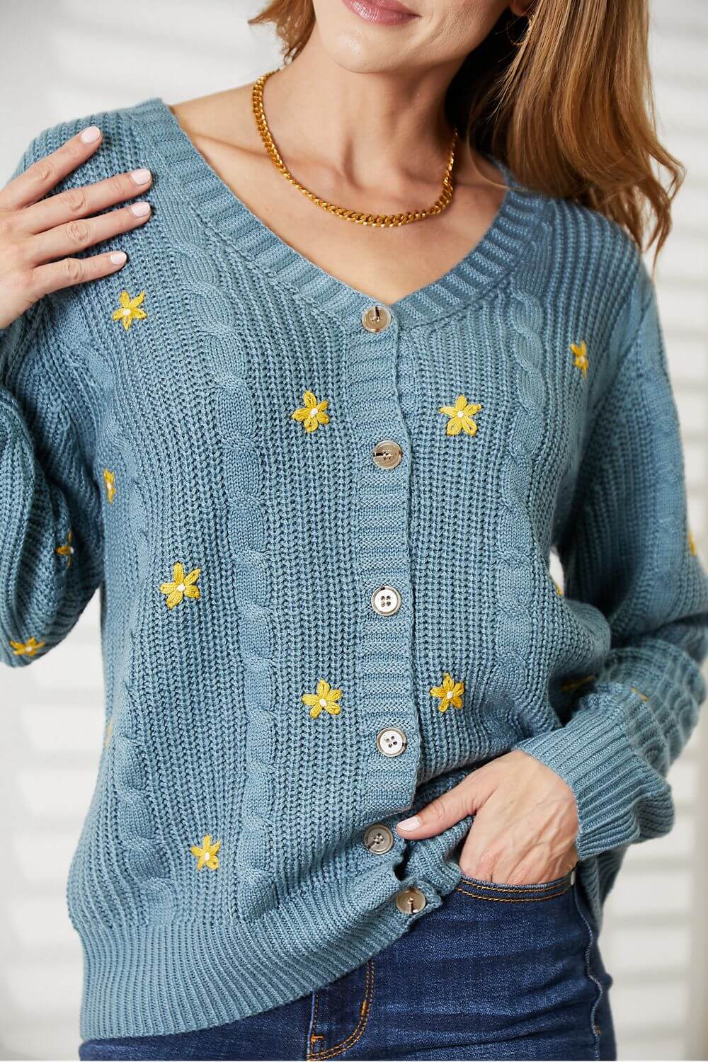 Woman wearing a HEYSON full-size floral embroidered cable cardigan in blue with yellow flowers, showcasing cozy elegance and charm.