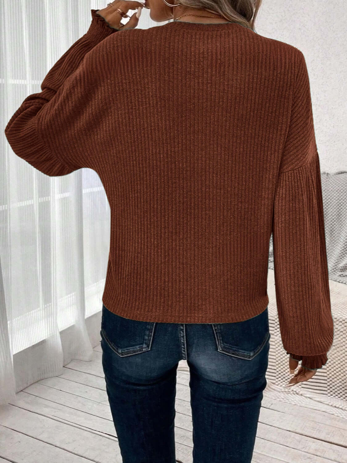 Woman wearing Bella Road Ribbed Round Neck Lantern Sleeve T-Shirt in brown, back view, paired with blue jeans in a casual setting.