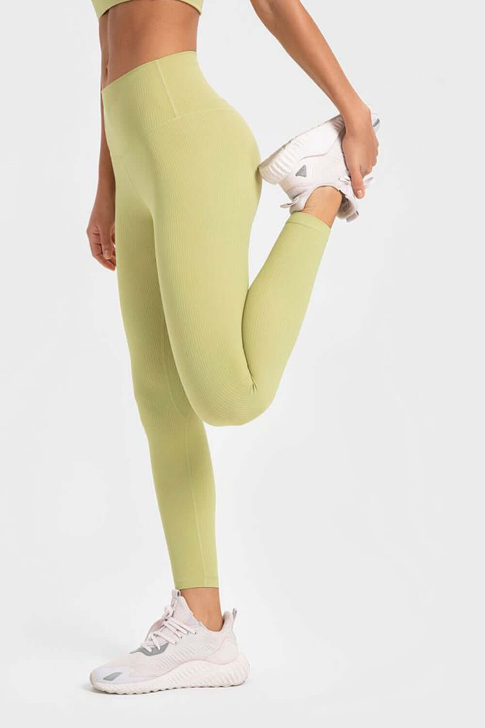 Model stretching in Millennia highly stretchy wide waistband yoga leggings in lemon color, showcasing flexibility and comfort.