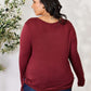 Woman wearing a maroon drawstring round neck long sleeve top, shown from the back.