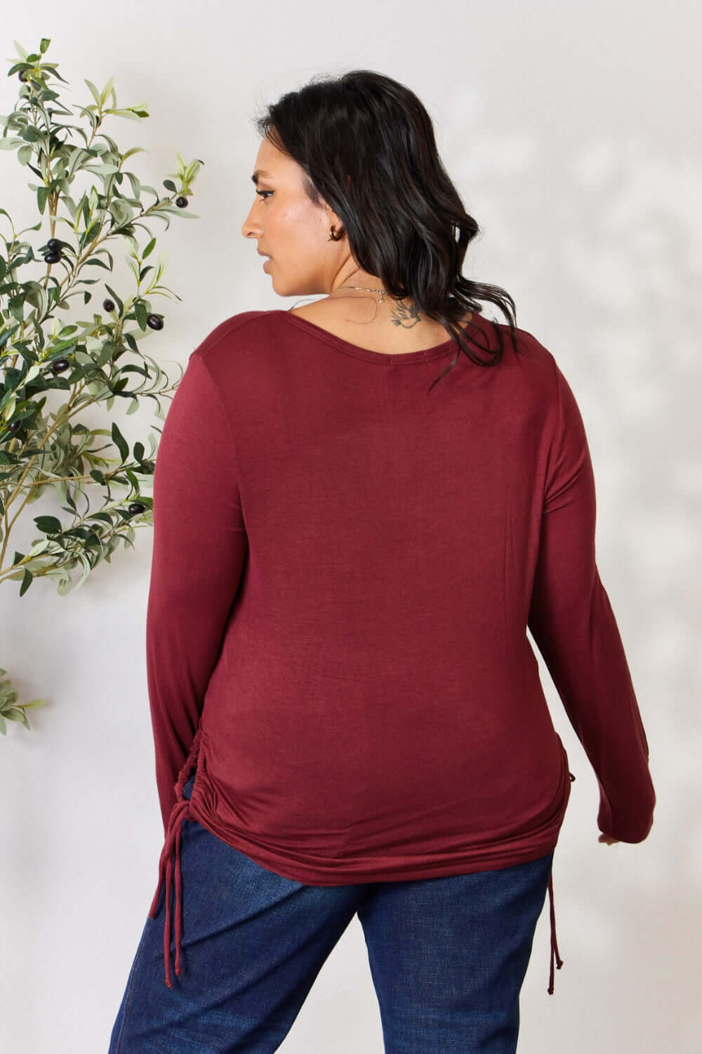 Woman wearing a maroon drawstring round neck long sleeve top, shown from the back.