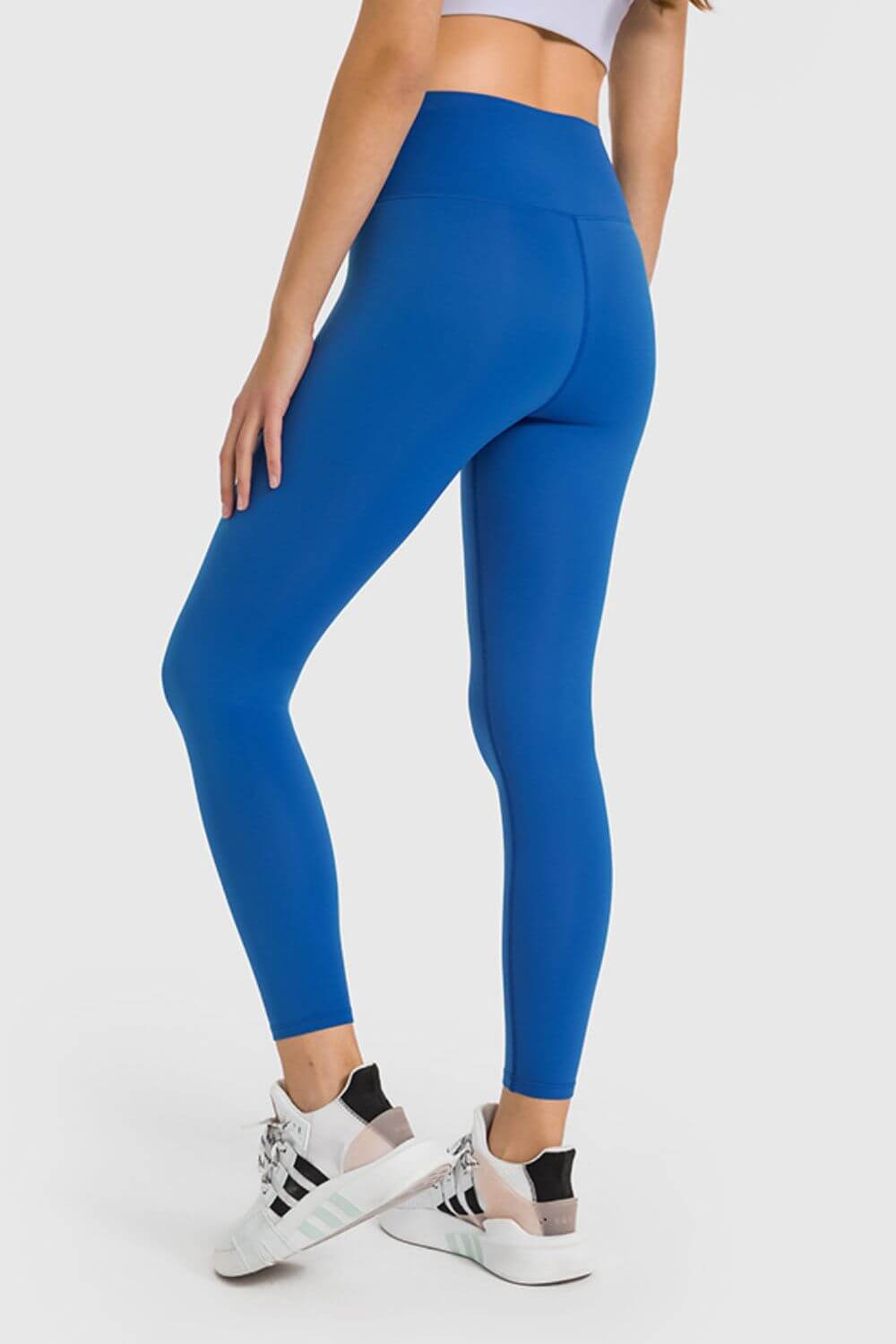 A woman wearing blue high waist ankle-length yoga leggings, showcasing a comfortable fit perfect for workouts.