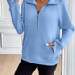 Woman wearing Ivy Lane Half Zip Raglan Sleeve Sweatshirt in light blue with black shorts standing indoors