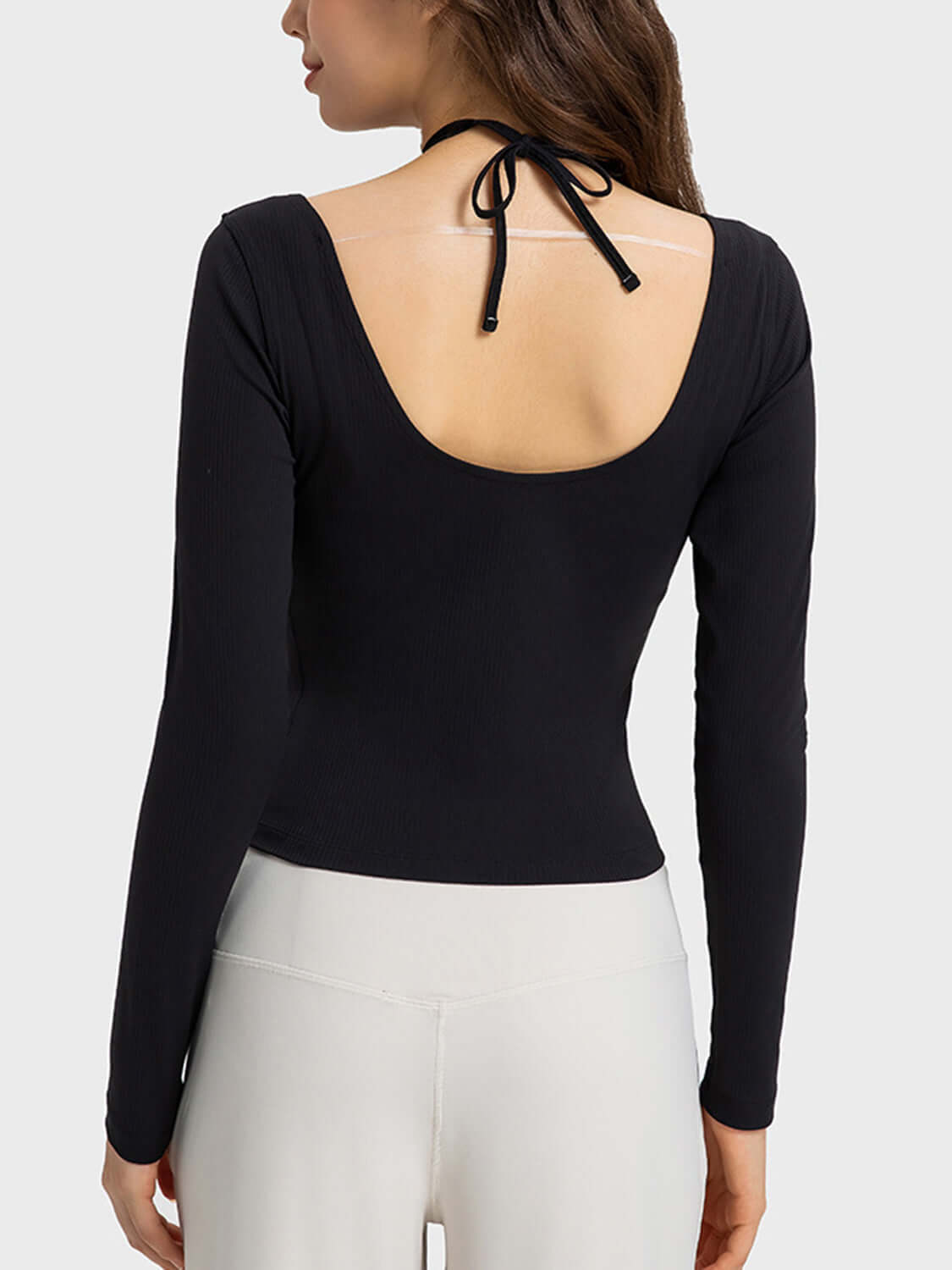 Back view of Millennia Halter Neck Long Sleeve Sporty Top, featuring a stylish tied design and sleek black fabric.