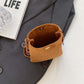 Bella Road Suede Snap Down Crossbody Bag on gray blazer, next to LIFE magazine and clear eyeglasses.